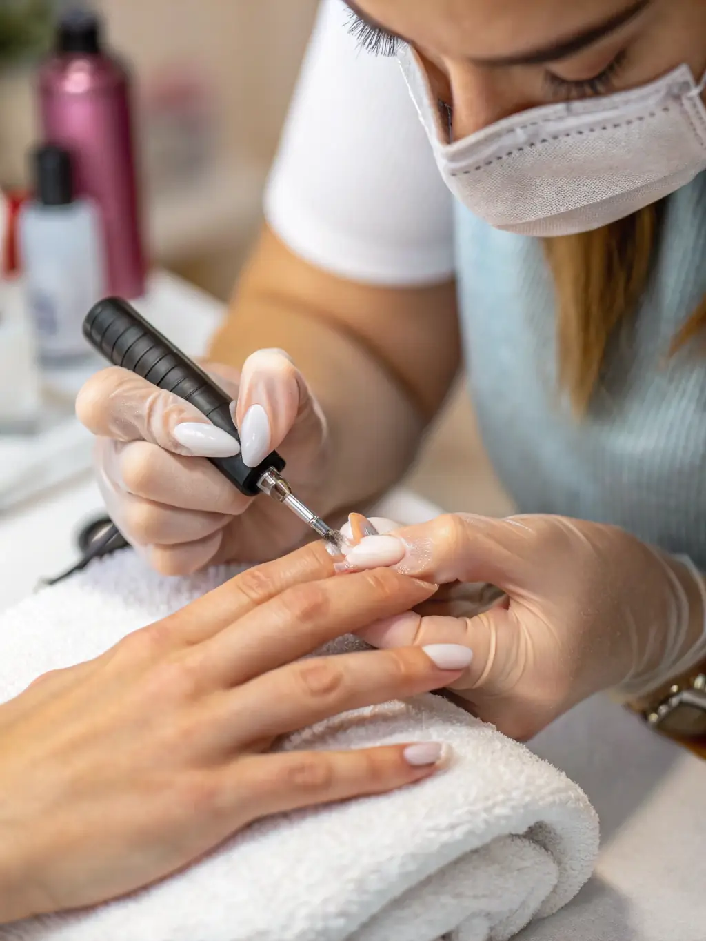 Close-up of a technician applying gel polish to a client's nails, showcasing the precision and vibrant color options available at J Nails & Spa.